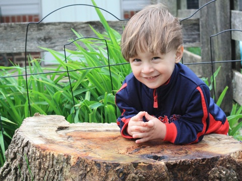 Boy on a stump, smiling at you too.